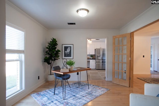 office area with light wood-style floors, baseboards, visible vents, and crown molding