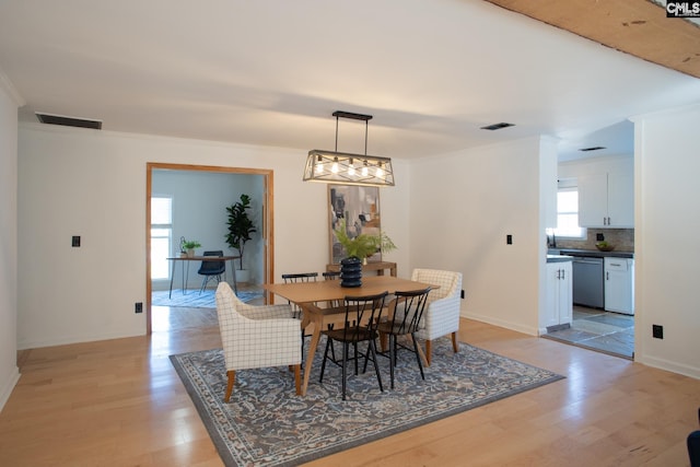 dining room with visible vents, crown molding, light wood-style flooring, and baseboards