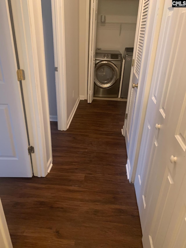 hall featuring separate washer and dryer, dark wood-type flooring, and baseboards