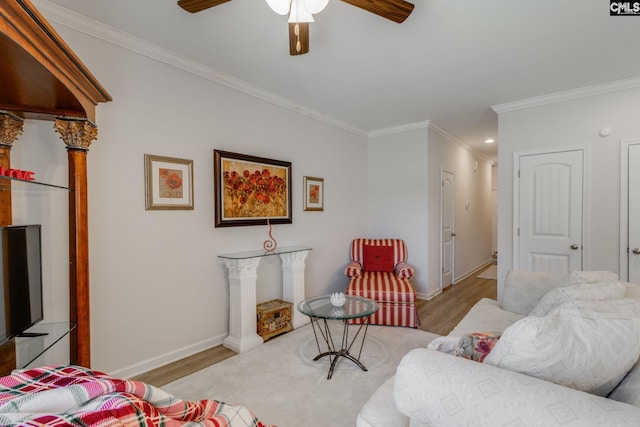 living area with a ceiling fan, crown molding, baseboards, and wood finished floors