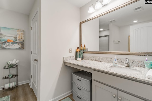 bathroom with visible vents, vanity, baseboards, and wood finished floors