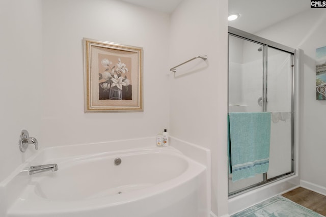 bathroom with a garden tub, wood finished floors, and a stall shower