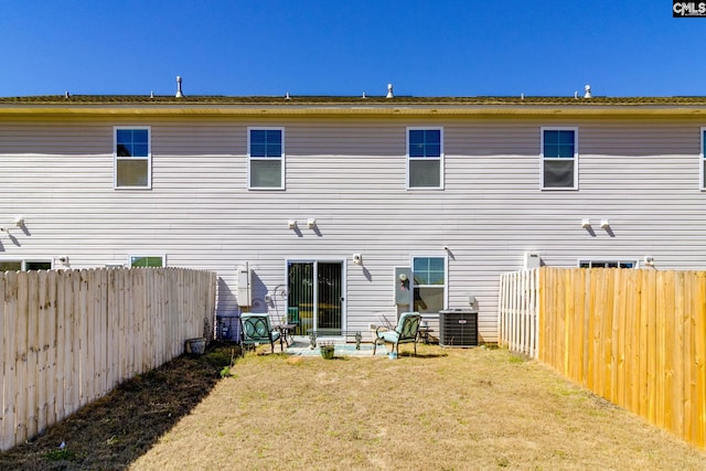 back of property featuring central air condition unit, a patio area, a fenced backyard, and a yard