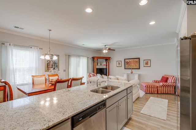 kitchen featuring light wood-style flooring, a sink, visible vents, ornamental molding, and appliances with stainless steel finishes