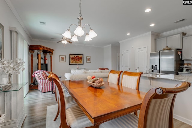 dining room featuring light wood finished floors, visible vents, and ornamental molding