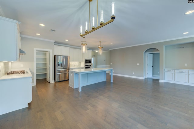 kitchen featuring appliances with stainless steel finishes, arched walkways, light countertops, and a kitchen island with sink