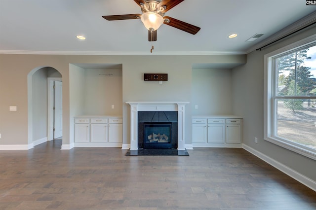 unfurnished living room with arched walkways, a fireplace, baseboards, dark wood finished floors, and crown molding