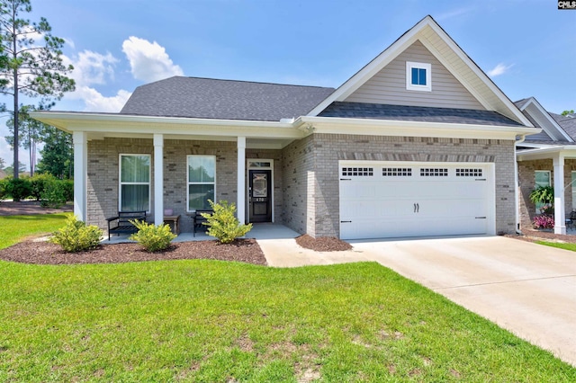 view of front of home with a porch, a garage, brick siding, driveway, and a front lawn