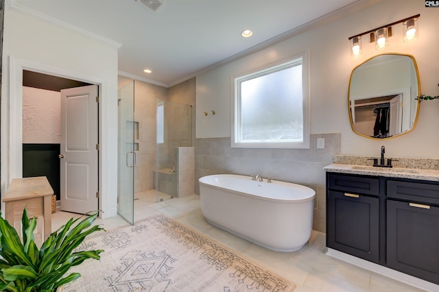 full bath with a stall shower, ornamental molding, vanity, a freestanding tub, and tile walls