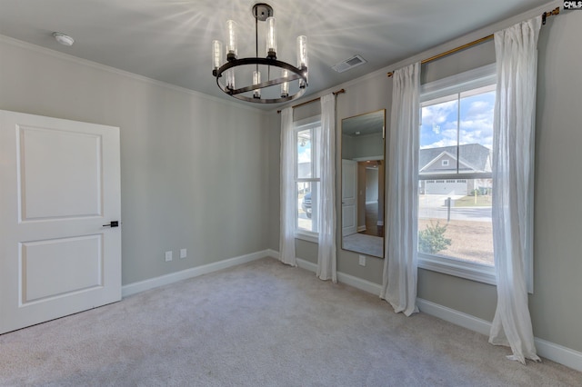 carpeted spare room with crown molding, baseboards, visible vents, and a notable chandelier