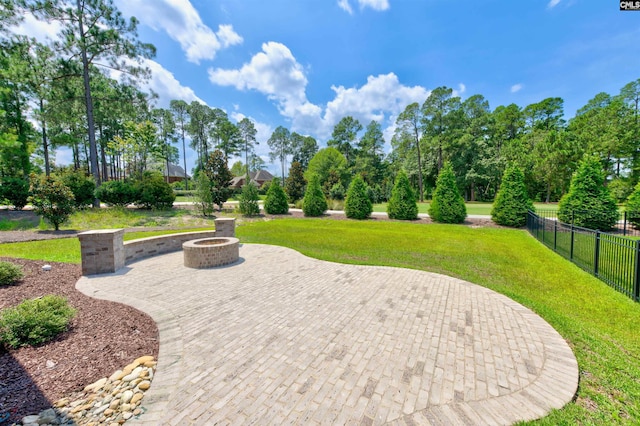 view of community with an outdoor fire pit, a patio area, fence, and a lawn