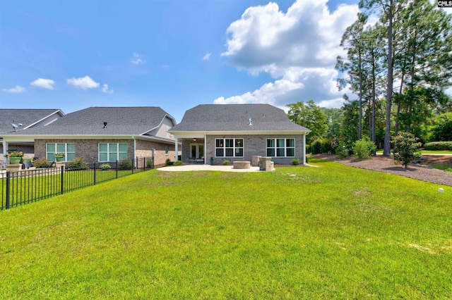 back of house featuring a patio, brick siding, a lawn, and fence