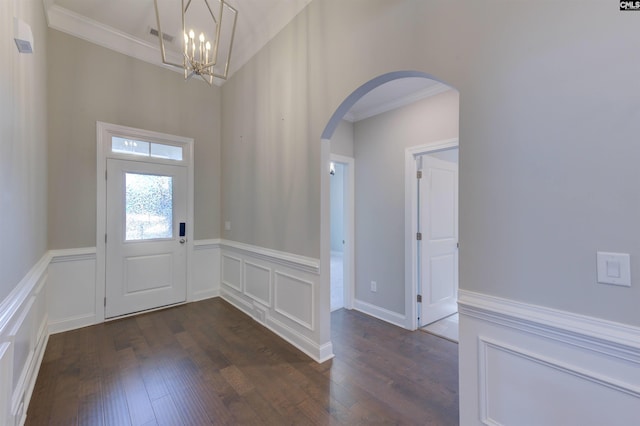 foyer entrance with arched walkways, dark wood-style flooring, a wainscoted wall, and crown molding