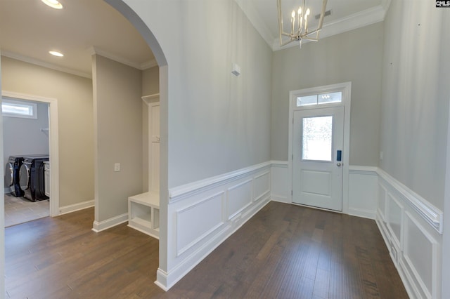 entrance foyer featuring arched walkways, ornamental molding, dark wood-type flooring, independent washer and dryer, and a decorative wall