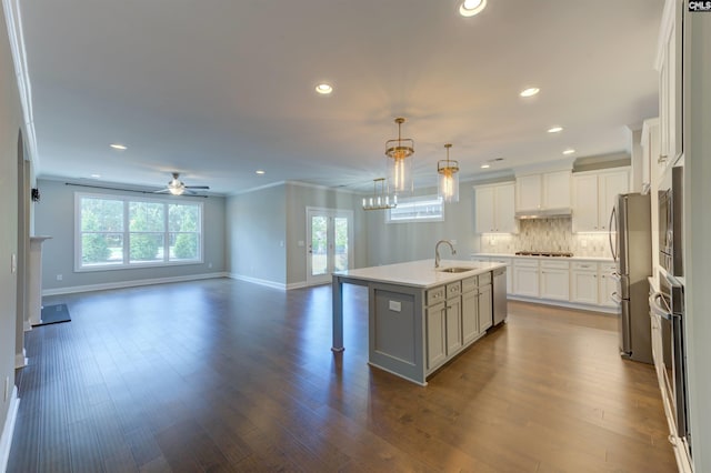 kitchen featuring decorative backsplash, open floor plan, dark wood-style flooring, a kitchen island with sink, and a sink