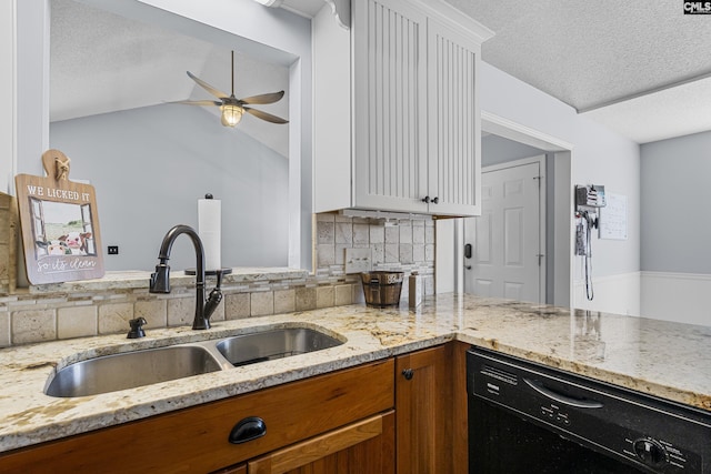 kitchen featuring a ceiling fan, dishwasher, light stone counters, white cabinetry, and a sink