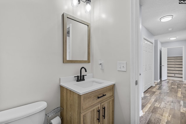 bathroom featuring a textured ceiling, wood finished floors, vanity, and toilet