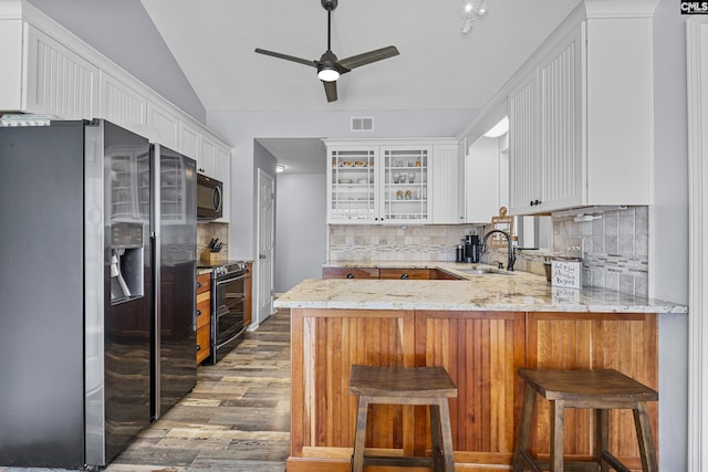 kitchen featuring stainless steel appliances, visible vents, vaulted ceiling, a sink, and a peninsula