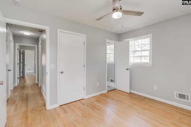 unfurnished bedroom featuring attic access, light wood-type flooring, visible vents, and baseboards