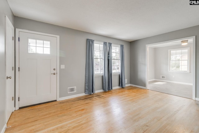 foyer entrance with light wood-type flooring, visible vents, and baseboards