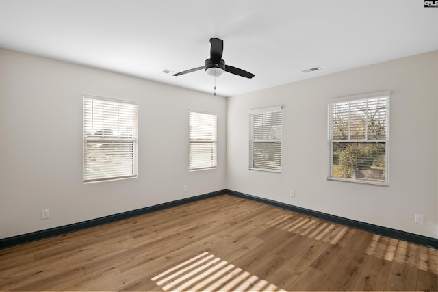 unfurnished room with a ceiling fan, light wood-type flooring, visible vents, and baseboards