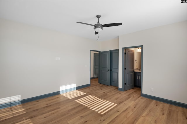 unfurnished bedroom with light wood-style flooring, baseboards, ceiling fan, and ensuite bathroom