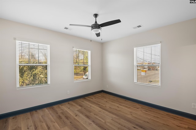 spare room featuring baseboards, visible vents, and wood finished floors