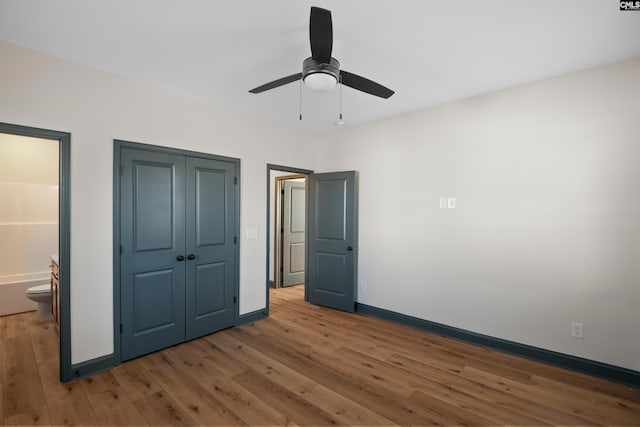 unfurnished bedroom with ceiling fan, connected bathroom, light wood-style flooring, baseboards, and a closet