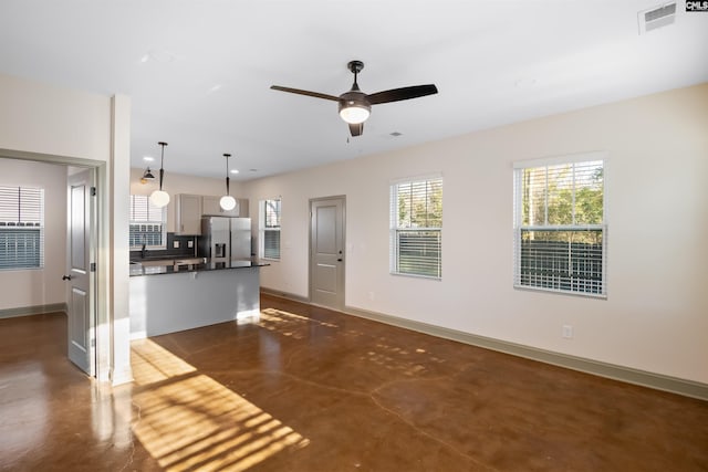 unfurnished living room featuring a wealth of natural light, concrete floors, visible vents, and baseboards