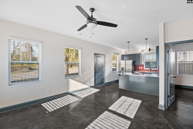 kitchen featuring light countertops, stainless steel refrigerator with ice dispenser, baseboards, and finished concrete flooring