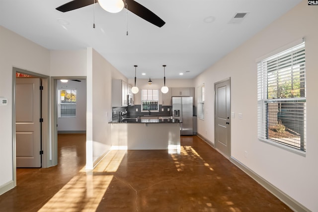 kitchen with stainless steel appliances, finished concrete floors, ceiling fan, a peninsula, and baseboards