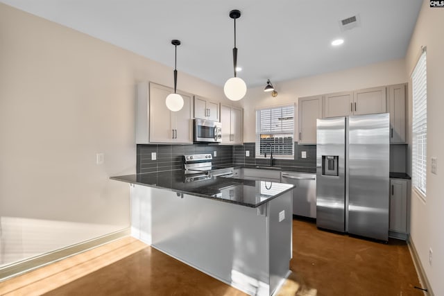 kitchen featuring stainless steel appliances, concrete floors, a peninsula, and decorative backsplash