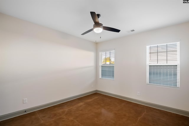 spare room with concrete flooring, ceiling fan, visible vents, and baseboards