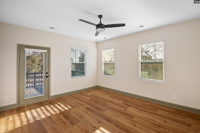 spare room with a wealth of natural light, visible vents, and wood finished floors