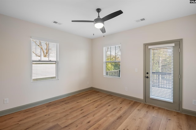 empty room with ceiling fan, light wood-type flooring, visible vents, and baseboards