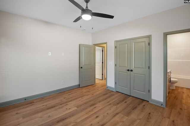 unfurnished bedroom featuring a closet, light wood-style flooring, ceiling fan, ensuite bath, and baseboards