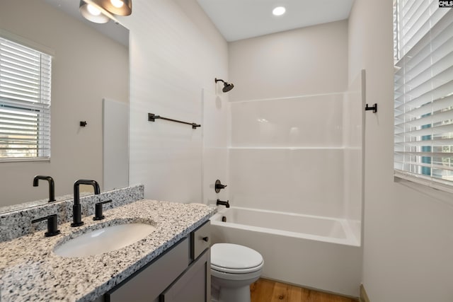 bathroom featuring toilet, a healthy amount of sunlight, vanity, and shower / bathing tub combination