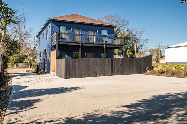 rear view of property featuring driveway and fence