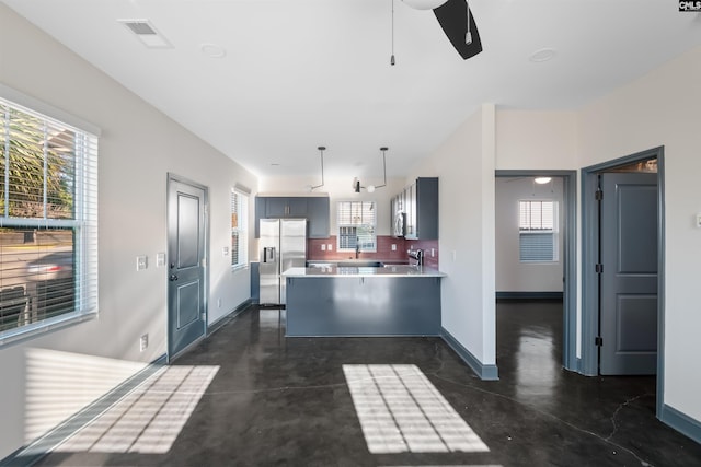 kitchen featuring a peninsula, a ceiling fan, finished concrete flooring, light countertops, and stainless steel refrigerator with ice dispenser