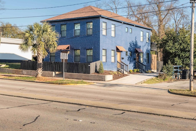 view of front of house featuring brick siding and fence