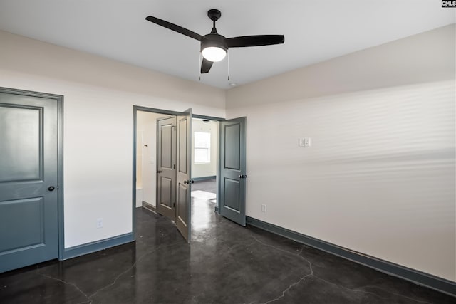 unfurnished room featuring concrete flooring, a ceiling fan, and baseboards