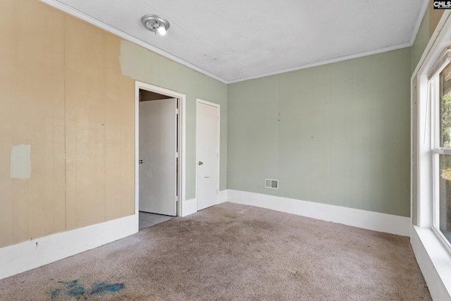 carpeted empty room with visible vents and crown molding