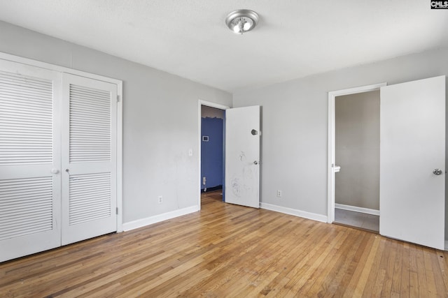 unfurnished bedroom featuring a closet, baseboards, and light wood finished floors