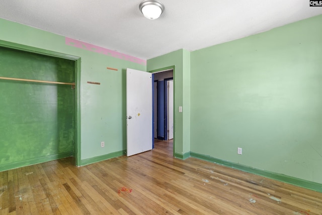 unfurnished bedroom featuring a closet, wood-type flooring, and baseboards