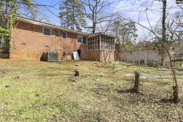 back of property featuring a sunroom, brick siding, and central air condition unit