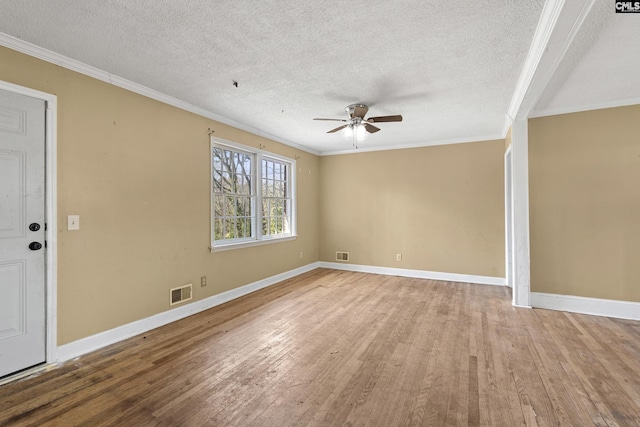 empty room with ornamental molding, a ceiling fan, visible vents, and wood finished floors