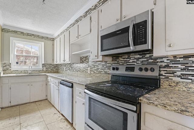 kitchen featuring light tile patterned floors, backsplash, appliances with stainless steel finishes, a sink, and a textured ceiling