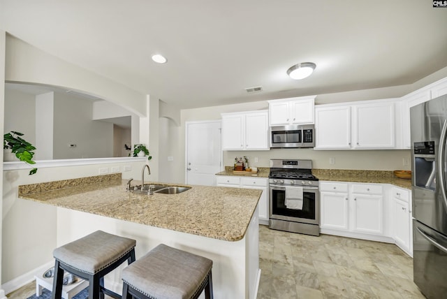 kitchen with a sink, visible vents, white cabinetry, appliances with stainless steel finishes, and a kitchen bar