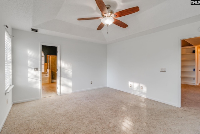 empty room featuring baseboards, a raised ceiling, visible vents, and light colored carpet