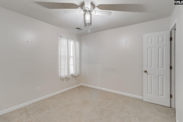 carpeted empty room with baseboards, visible vents, a ceiling fan, and a textured ceiling